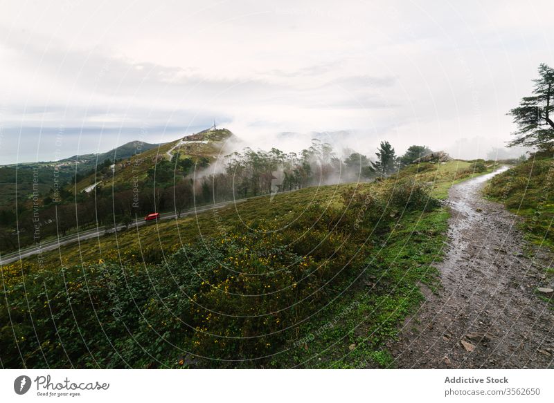 Hügeliges Gelände mit Straße an nebligem Tag Nebel Berge u. Gebirge Tal Windstille grün nass Landschaft Berghang ruhig wolkig Morgen Natur Umwelt Weg Route