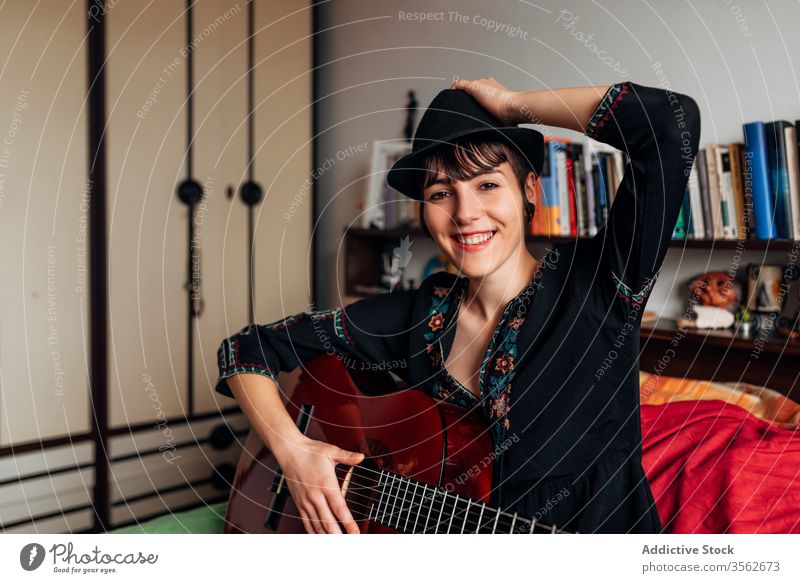 Lächelnde Frau spielt Gitarre im Schlafzimmer spielen Musik akustisch Instrument Windstille ruhig trendy Melodie Klang Bett sitzen Hobby Musiker Gesang