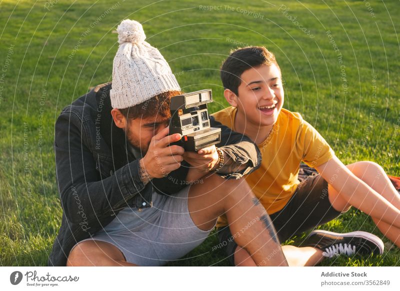 Vater fotografiert Frau mit Kind im Park Familie fotografieren Zusammensein Wiese Liebe Partnerschaft Glück positiv Fotokamera Gras sofort heiter Herbst jung