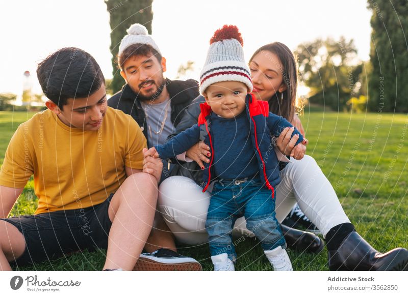 Glückliche Familie mit Kindern, die sich auf der grünen Wiese ausruhen Zusammensein Park Liebe Gras Porträt Partnerschaft positiv heiter Herbst jung Kleinkind