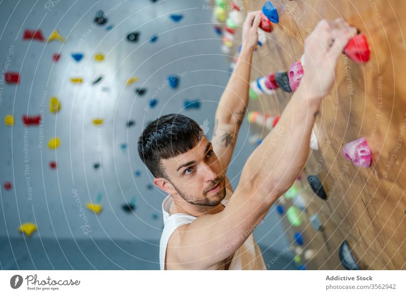 Fokussierter männlicher Kletterer an der Wand hängend Aufstieg Mann Sport Training Felsbrocken Gerät Fitnessstudio Aktivität Athlet Hobby extrem stark Club