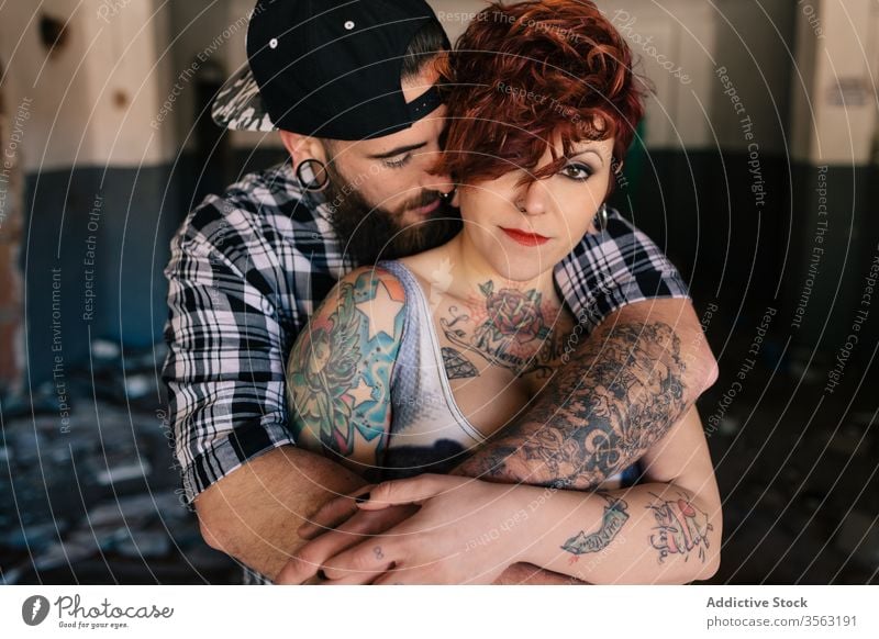 Glückliches junges Paar umarmt fast verwittertes Gebäude Liebe Umarmen Hipster Straße schäbig Zusammensein Umarmung Partnerschaft Tattoo Freund Freundin