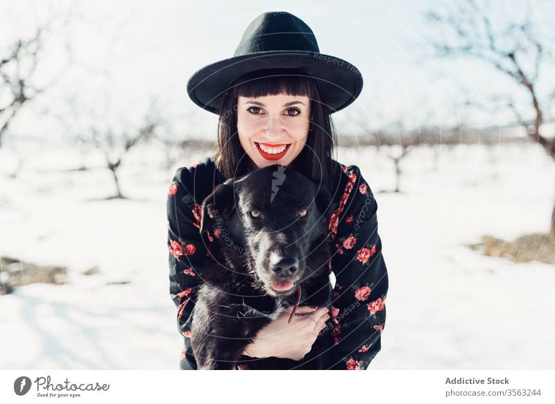 Stilvolle Frau mit Hund im Winterfeld Feld trendy Schnee schwarz Zusammensein Haustier Mode Park sich[Akk] entspannen Wald Baum Windstille Hut züchten kalt