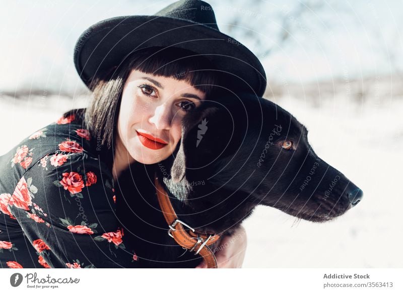 Stilvolle Frau mit Hund im Winterfeld Feld trendy Schnee schwarz Zusammensein Haustier Mode Park sich[Akk] entspannen Wald Baum Windstille Hut züchten kalt