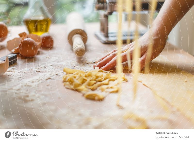 Nicht erkennbare Frau mit geschnittener roher Pasta Spätzle selbstgemacht Teigwaren Gurt dünn Streifen Gebäck Koch Tisch Mehl Küchengeräte rollen Eierschale