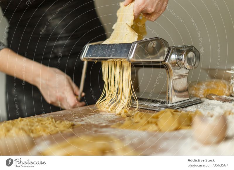 Gesichtslose Köchin schneidet Gebäck mit einer Nudelmaschine Frau Maschine Spätzle rollen Streifen geschnitten dünn benutzend roh Form Teigwaren Gerät Koch Mehl