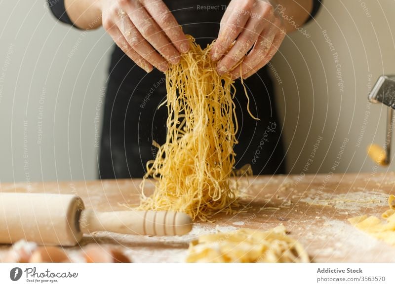 Nicht erkennbare Frau mit geschnittener roher Pasta Spätzle selbstgemacht Teigwaren Gurt dünn Streifen Gebäck Koch Tisch Mehl Küchengeräte rollen Eierschale