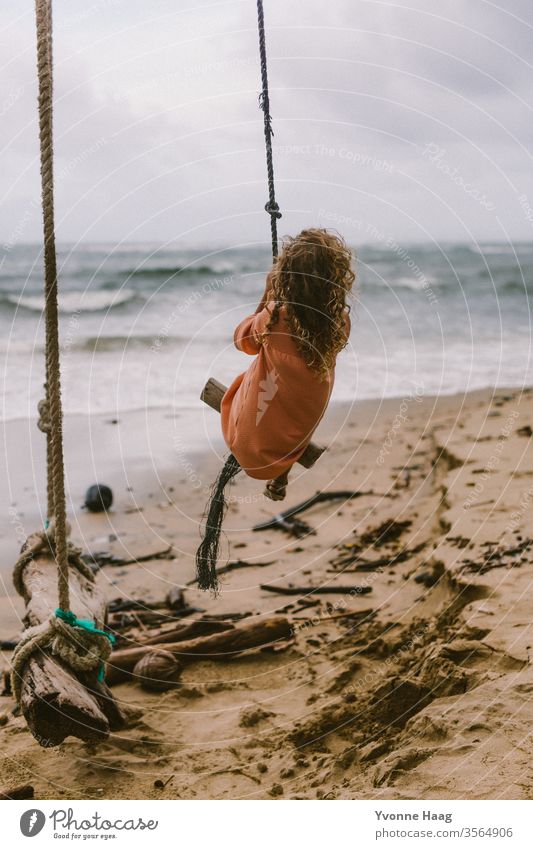 Mädchen sitzt auf einer Schaukel und schaukelt dem Meer entgegen Hawaii Hawaiiblume schaukeln Schaukelnd Freude Spielen Außenaufnahme Farbfoto Spielplatz