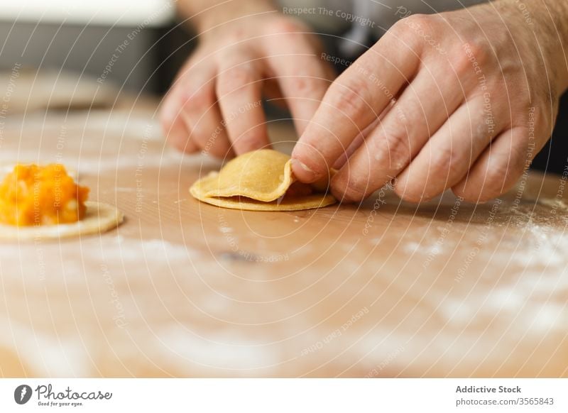 Erntehelfer, der Ravioli mit Kürbisfüllung füllt Teigwaren Zeug vorbereiten kreisen Koch Tisch rund hölzern Prozess Küche Lebensmittel kulinarisch selbstgemacht