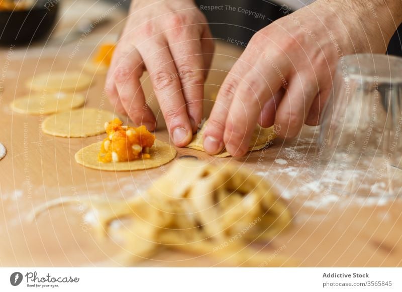 Erntehelfer, der Ravioli mit Kürbisfüllung füllt Teigwaren Zeug vorbereiten kreisen Koch Tisch rund hölzern Prozess Küche Lebensmittel kulinarisch selbstgemacht