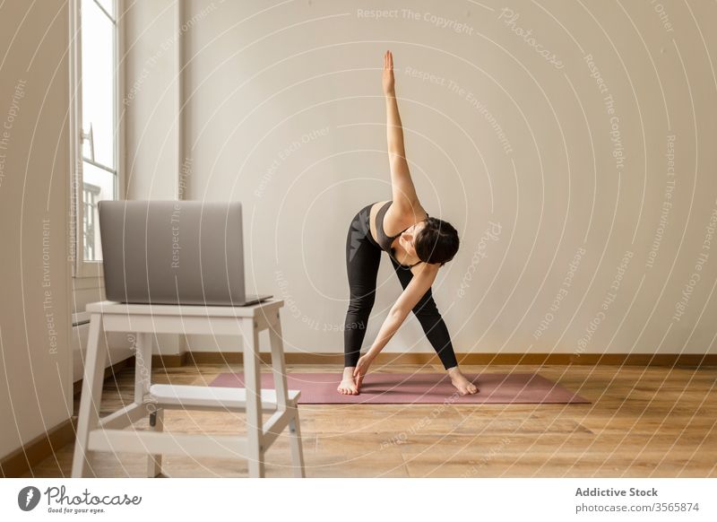 Ruhige Frau steht beim Yoga in abwärts gerichteter Hundehaltung Dehnung beweglich Gesunder Lebensstil heimwärts nach unten gerichteter Hund Laptop Tutorial