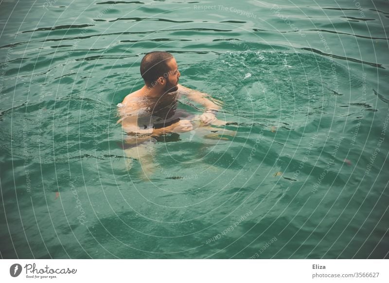 Ein Mann beim Baden im Wasser Schwimmen kalt kühl Schwimmer Meer See baden blau Sommer Schwimmen & Baden braunhaarig Urlaub bedrohlich Luft holen Gefahr dunkel