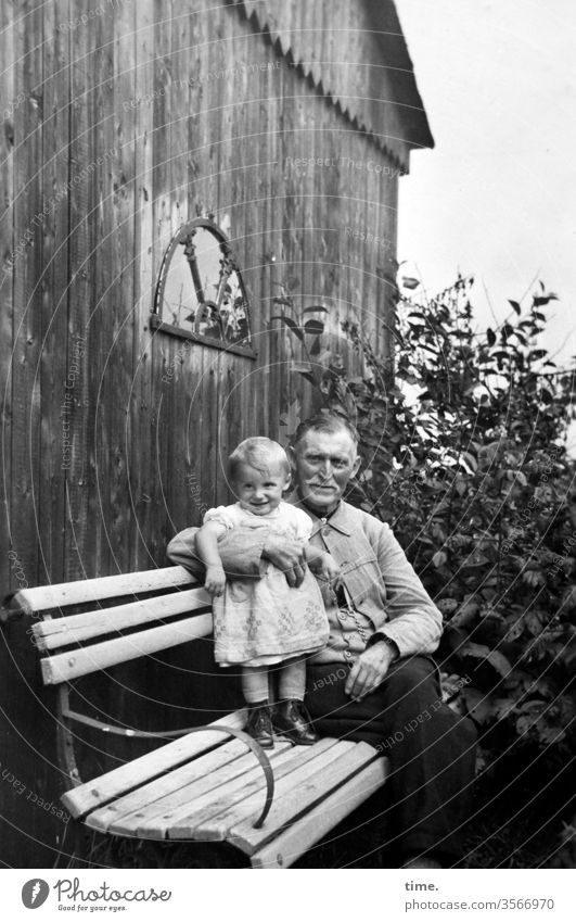 intergenerativer Dialog (II) portrait kleidung damals früher alt nostalgie blick kurzhaarig anzug opa enkel sitzbank holzhaus garten busch halten sitzen