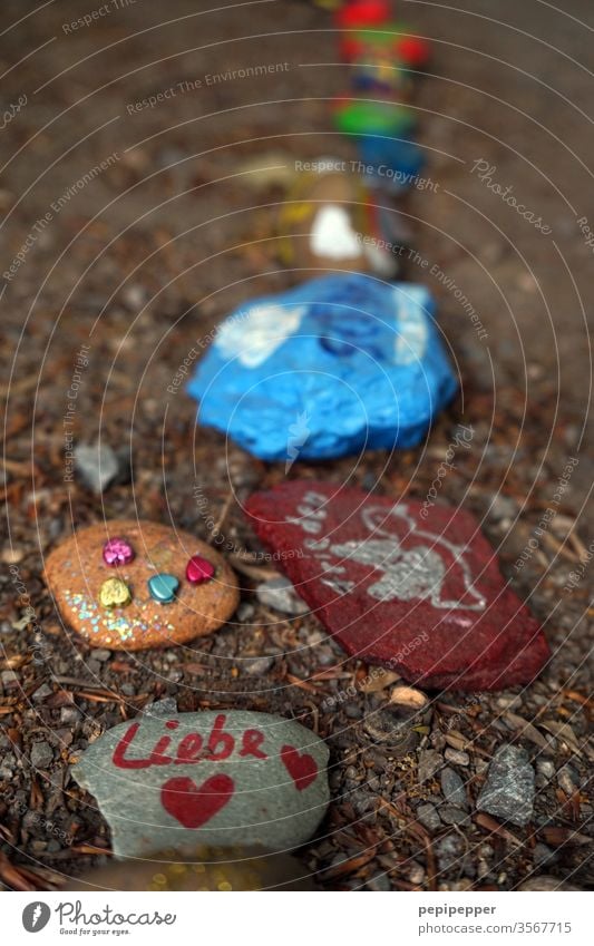 Bunte Steine in einer Reihe liegend Liebe Herz rot Makroaufnahme heart Frieden Gefühle Bemalung gemalt bunt Glück Farbfoto Detailaufnahme Freude Albstones