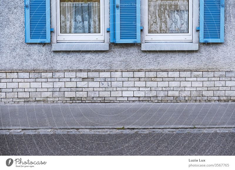 Graue Fassade mit leuchtend blauen Fensterläden Wand Straße Tristesse Stadt urban Außenaufnahme Menschenleer Tag Mauer Wege & Pfade Textfreiraum unten Farbfoto