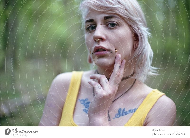 Analoges Portrait einer jungen Frau mit Piercings, Tätowierungen und Tunnel Mädchen blond Schmuck Assecoires Schulter Shirt Hemd schön draussen schauen