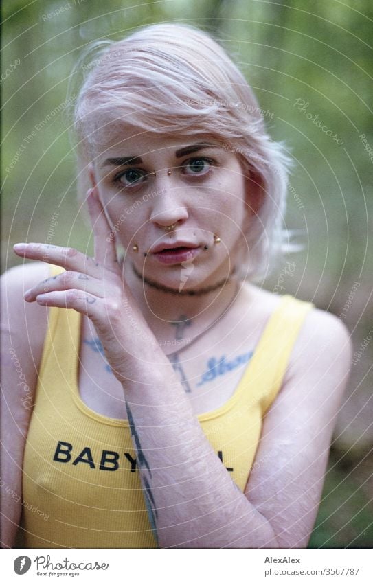 Analoges Portrait einer jungen Frau mit Piercings, Tätowierungen und Tunnel Mädchen blond Schmuck Assecoires Schulter Shirt Hemd schön draussen schauen