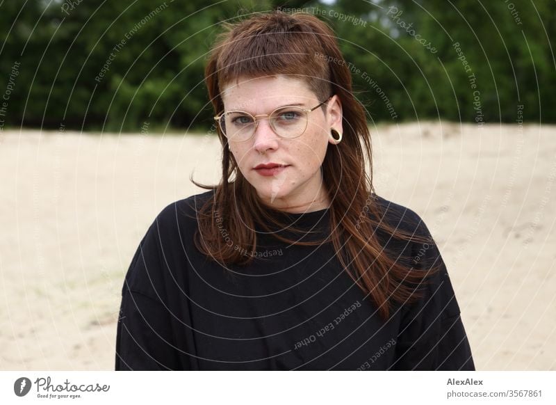 Portrait einer jungen Frau im Park Jugendliche schön stark alternativ groß Piercing Haut intensiv Blick schauen beaobachten stehen schlank ästhetisch sportlich