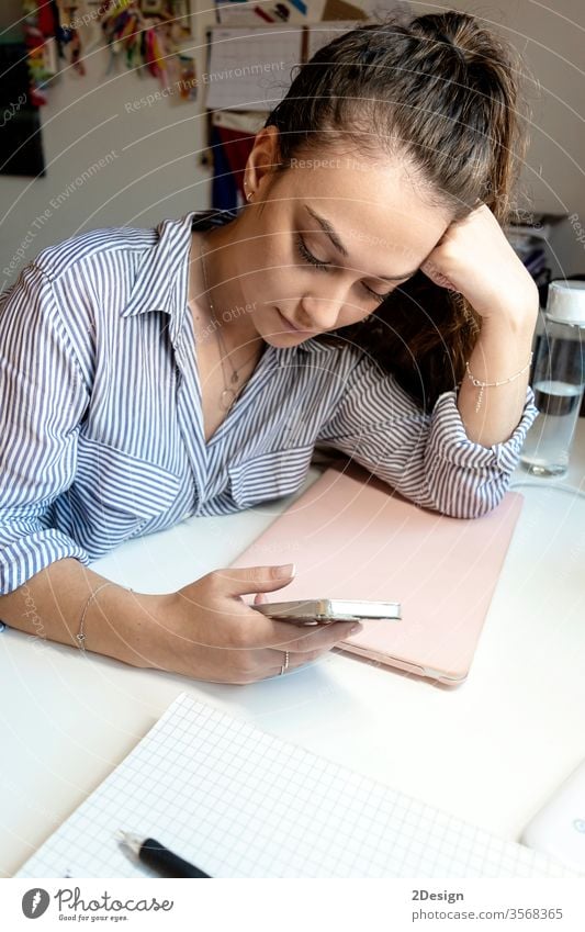 Junge Frau, die an einem Laptop sitzt und ein Smartphone benutzt. Computer Büro Business Person Schreibtisch Technik & Technologie Geschäftsfrau jung