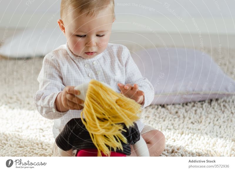 Kleines Kind spielt mit Spielzeugpuppe Kleinkind spielen wenig Kindheit Vorschule bezaubernd Gewebe Puppe Spaß haben niedlich lässig Stock sitzen neugierig