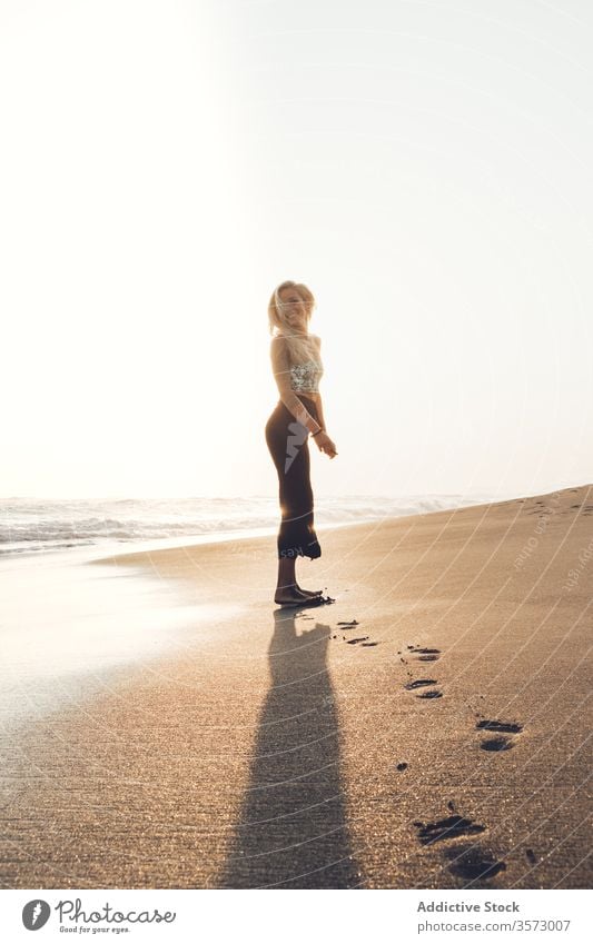 Schlankes junges Weibchen am feuchten Sandstrand stehend Frau Meereslandschaft Harmonie Einsamkeit Frieden winken Hipster nass MEER allein Küste Windstille