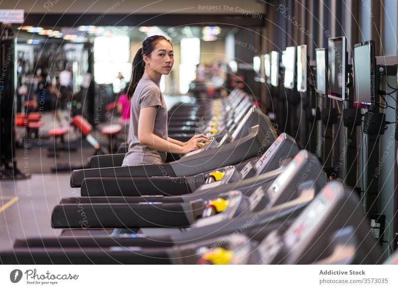 Junge ethnische Sportlerin läuft auf dem Laufband, während sie in einem modernen Fitnessstudio trainiert Frau laufen Herz Übung Athlet Training Gesundheit