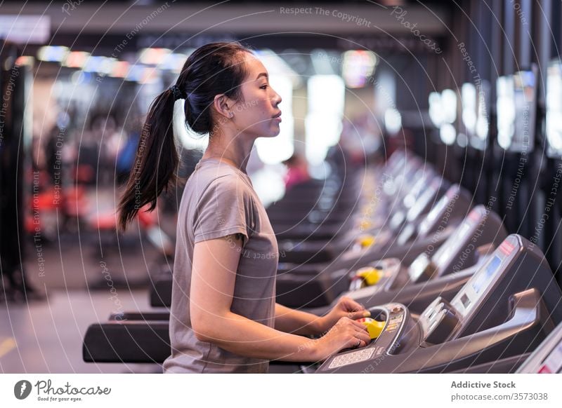 Junge ethnische Sportlerin läuft auf dem Laufband, während sie in einem modernen Fitnessstudio trainiert Frau laufen Herz Übung Athlet Training Gesundheit