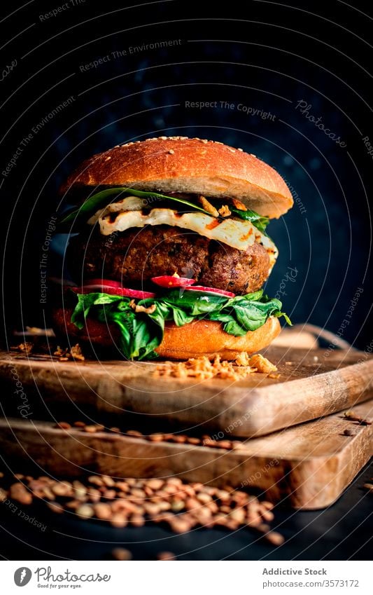 Vegane Linsen-Hamburger auf Holzbrettchen auf dunklem Hintergrund Feinschmecker Linsen-Burger Gemüse-Burger Fastfood Essen gebacken lecker natürlich Lifestyle