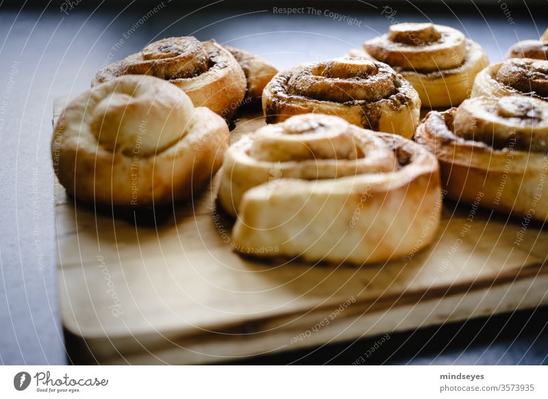 Zimtrollen auf einem Holzbrett Zimtbrötchen Hefegebäck Foodfotografie Lebensmittel Farbfoto frisch duftig lecker backen süß Backwaren Ernährung Zucker