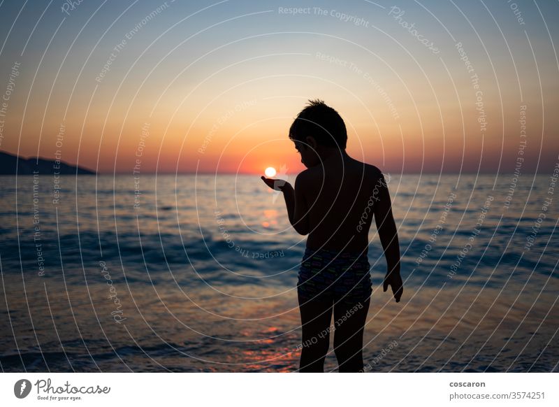 Kleiner Junge spielt mit der Sonne am Strand bei Sonnenuntergang aktiv schön sorgenfrei heiter Kind Kindheit Küste Küstenstreifen Abend Spaß Griechenland Hand