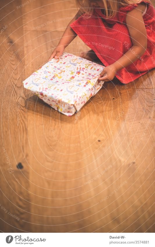 Geburtstag Kind packt ein Geschenk aus Mädchen Geburtstagsgeschenk Geschenke Freude Happy Birthday schenken Boden Parkettboden Holzboden auspacken natürlich