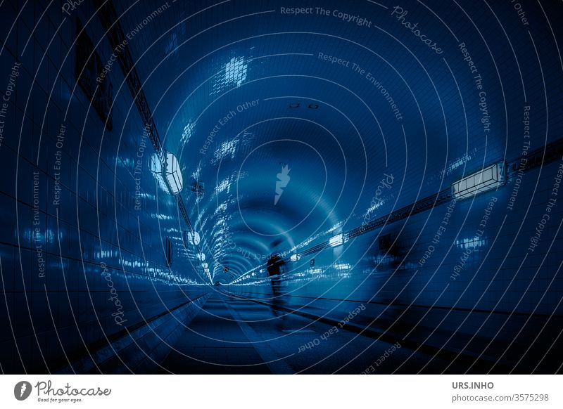 Fahradfahrer rast einsam durch einen dunklen blauen Tunnel Radfahrer beleuchtet dunkel Nacht Lampe Licht Unterführung unterirdisch Straße Fahrradfahrer Röhre