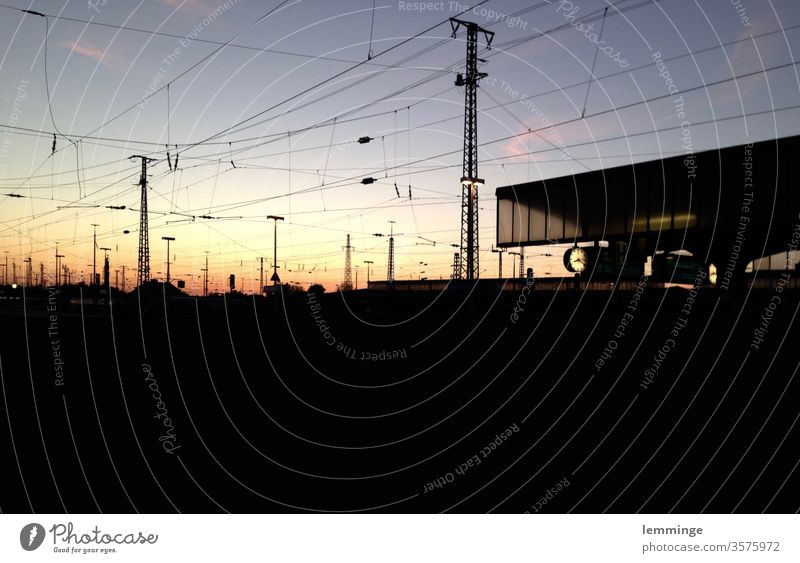 Dortmunder Bahnhof in der Dämmerung Gleise Dunkelheit Abend Nacht Bahnsteig Uhr Strommast Glas schwarz Außenaufnahme Eisenbahn Verkehr Bahnfahren Menschenleer