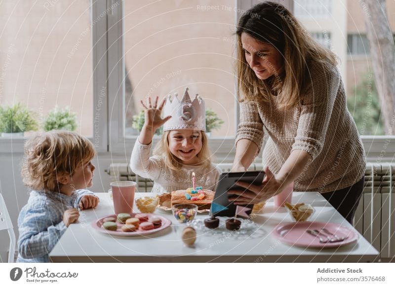 Fröhliches kleines Mädchen macht während der Geburtstagsfeier einen Videoanruf auf Tablet Mutter Tochter feiern Spaß Glück abgelegen heimwärts Entfernung