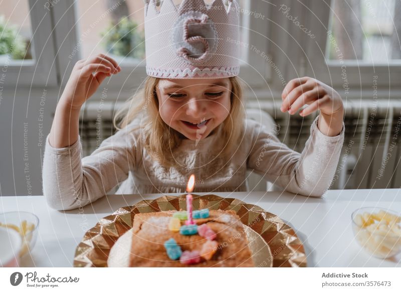 Kleines Mädchen bläst Kerze auf Geburtstagskuchen während einer Party zu Hause Kuchen Wunsch Schlag Glück feiern heimwärts Freude charmant Krone Filz dekorativ