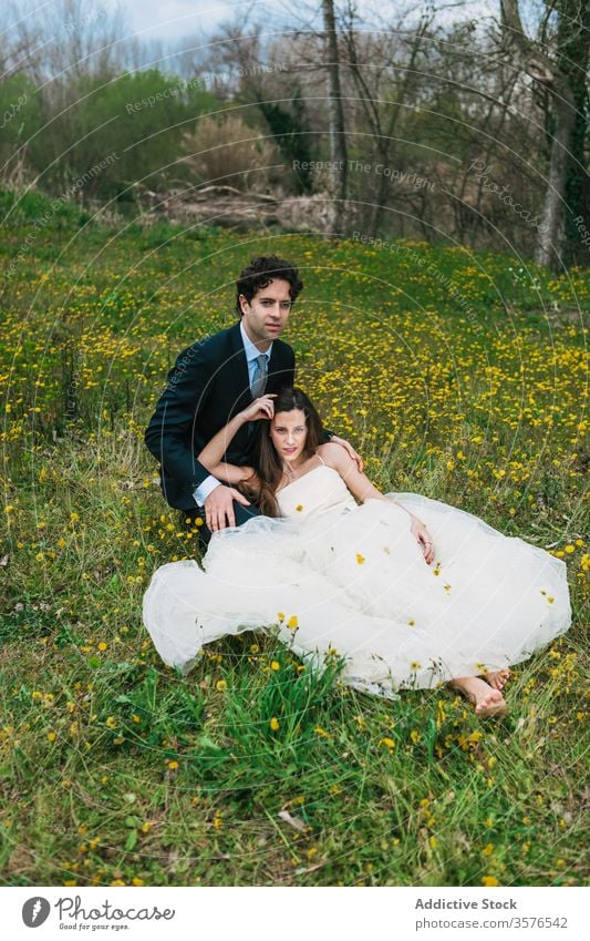 Jungverheiratete entspannen gemeinsam auf blühender Wiese Jungvermählter Paar Blüte Zusammensein Hochzeit Umarmen Braut striegeln Blume Rasen Umarmung