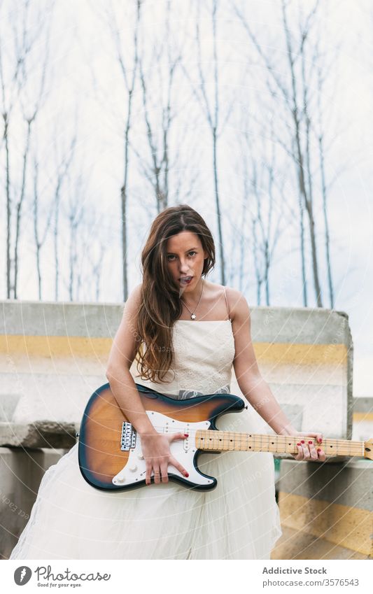 Stilvolle Braut spielt E-Gitarre in der Nähe eines verlassenen Gebäudes spielen elektrisch Jungvermählter Verlassen Hochzeit Felsen Frau Brautkleid Hochzeitstag