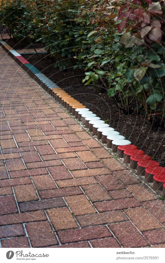 Weg durch den Vorgarten vorgarten bürgersteig gehweg stein ziegelstein mauerstein fuge poller grenze begrenzung hecke beet rabatte farbe bunt menschenleer