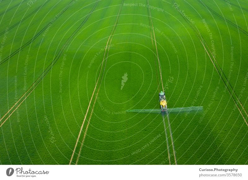 Grüne Felder. Luftaufnahme des Traktors, der die Chemikalien auf der großen grünen Wiese versprüht. Landwirtschaftlicher Frühlingshintergrund. Bereiche oben