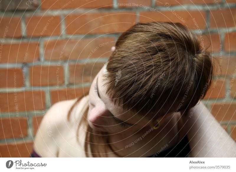 Portrait einer jungen Frau vor einer Backsteinwand frei wild heiter zuversichtlich Vertrauen Textfreiraum rechts Coolness Textfreiraum links Porträt