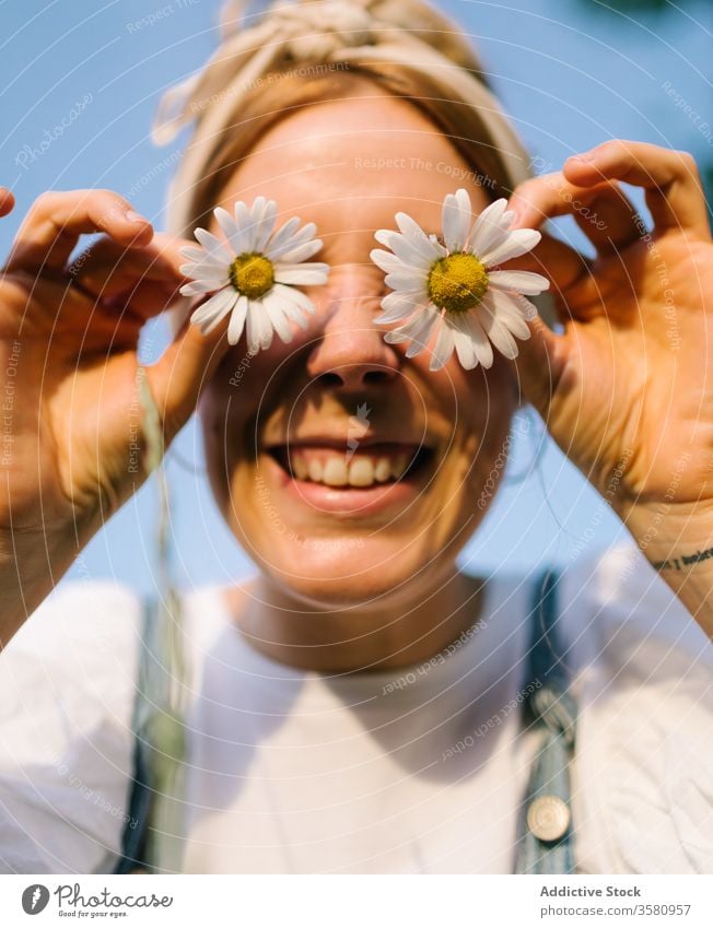 Fröhliche junge Dame, die die Augen mit Kamillenknospen bedeckt Frau frisch spielerisch Spaß Augen abdecken Glück rund so tun, als ob charmant Frühling Wiese