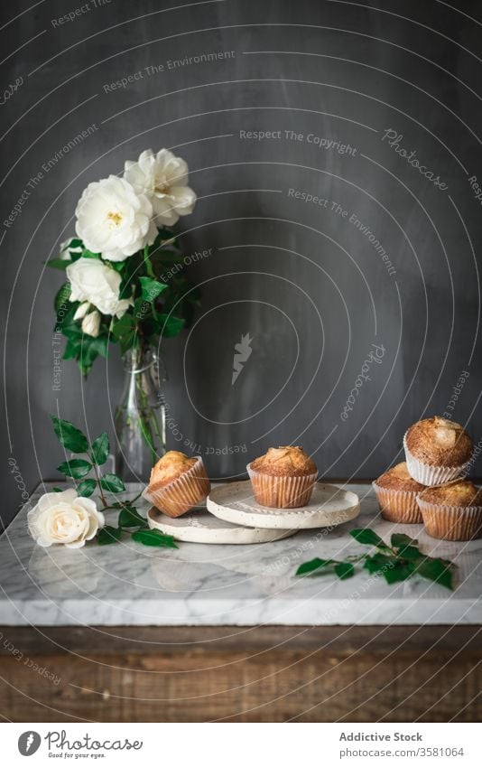 Köstliche Törtchen in Komposition mit duftenden weißen Blumen in Vase auf dem Tisch Cupcake Lebensmittel Leckerbissen Roséwein Mahlzeit Dessert Blumenstrauß