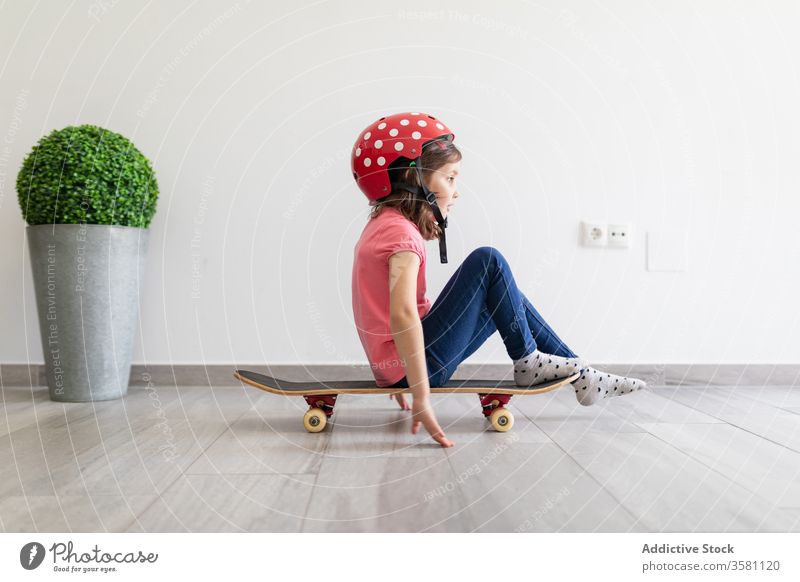 Glückliches Mädchen im Vorschulalter fährt zu Hause Skateboard heimwärts Spiel unterhalten Spaß Kind spielen Dekor Longboard Schutzhelm träumen zu Hause bleiben