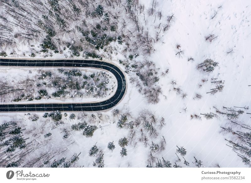 Kurvige, kurvenreiche, kurvenreiche Straße in schneebedecktem Wald, Luftaufnahme von oben. Winterlandschaft. Ansicht Antenne Top Dröhnen Schnee Landschaft Natur