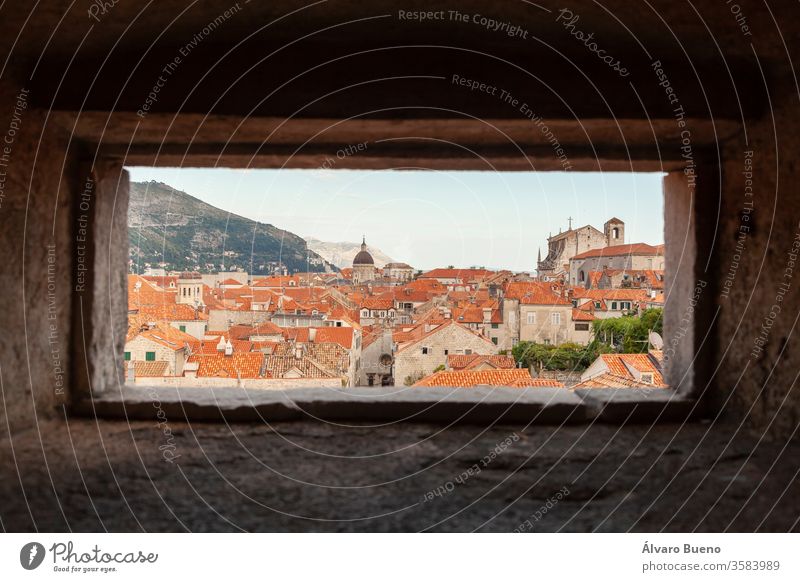 Orangefarbene Dächer von Dubrovnik, von der Wand aus gesehen, durch ein kleines Fenster, im Schatten der Nachmittagswolken, am Ufer der Adria. kleine Häuser