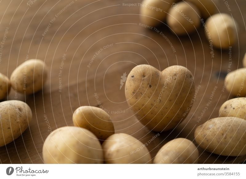 Frischer Kartoffel in Herzform auf braunem Holztisch Ernährung Essen Genuß Lebensmittel Nahrung Speise bio ernte gemüse gesund gesundheit hintergrund holz