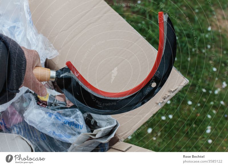 Hand mit Sichel Paket Wiese Verpackung Farbfoto Menschenleer Nahaufnahme Textfreiraum oben Textfreiraum rechts objekt der begierde auspacken