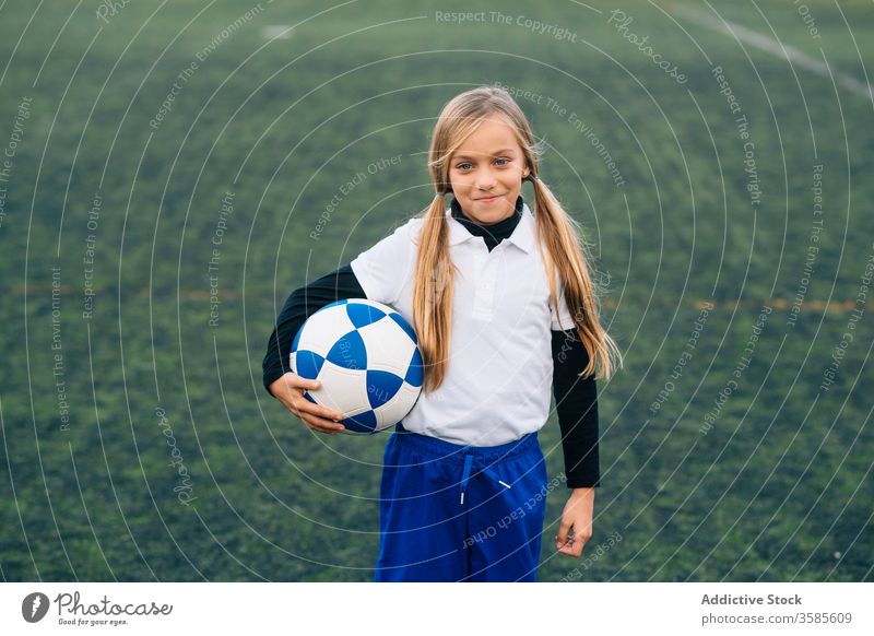 Glückliche junge Spielerin mit Ball in Fussballarena im Sportstadion Mädchen Fußball Feld Uniform Kind Club Kindheit Athlet Gerät Lächeln Schulmädchen heiter