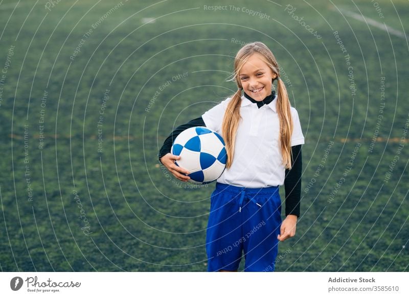 Glückliche junge Spielerin mit Ball in Fussballarena im Sportstadion Mädchen Fußball Feld Uniform Kind Club Kindheit Athlet Gerät Lächeln Schulmädchen heiter