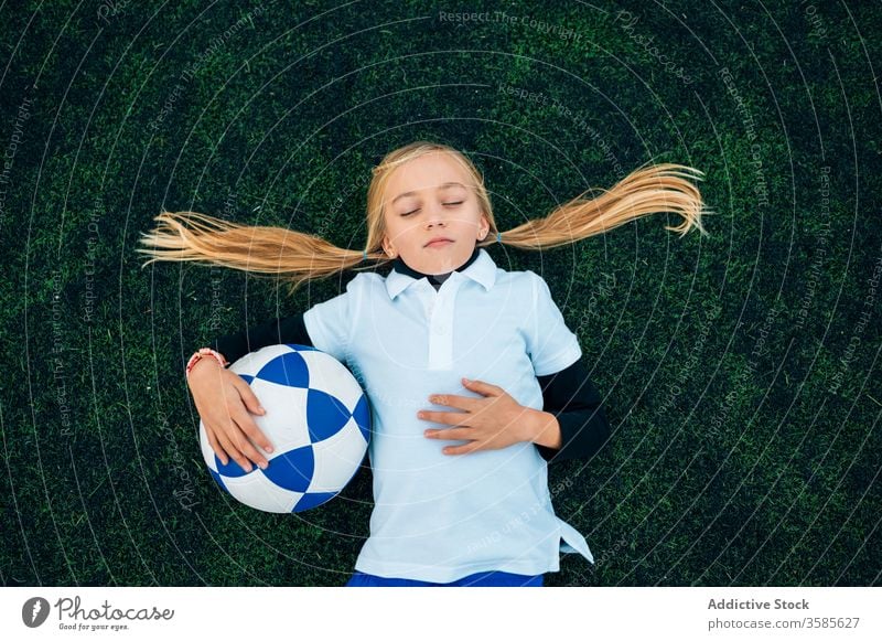 Fröhliche Spielerin mit Fussball entspannt auf dem Rasen Mädchen Fußball Lachen Feld sich[Akk] entspannen Ball Pferdeschwanz Stadion Kind Glück spielerisch